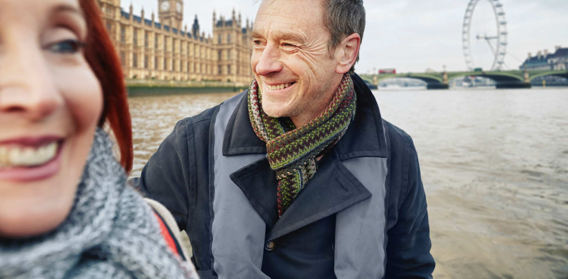 Man and woman smiling in front of London Parliament and London Eye