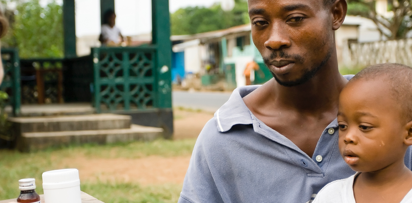 A young man and toddler looking in two different directions outside